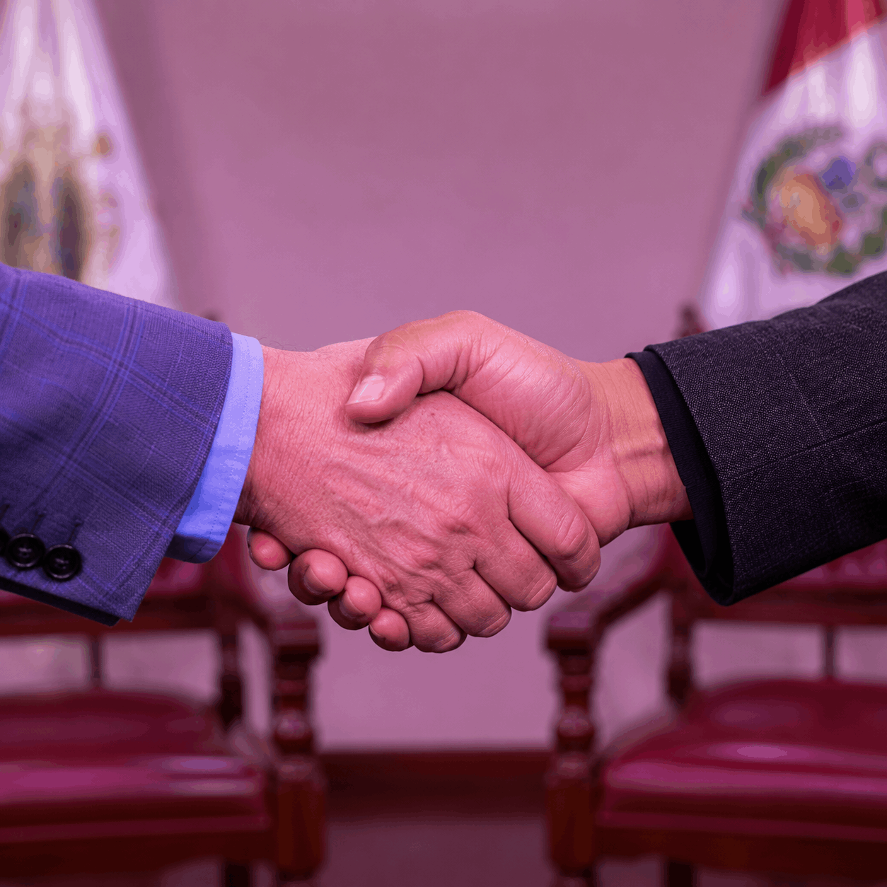 Dos personas se saludan con un apretón de manos en un estudio preparado para una conversación
